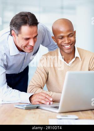 Your work is excellent. Two businesspeople working on a laptop together in the office. Stock Photo