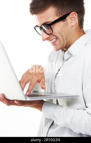 Hes the best hacker around. A nerdy hipster touching the keys on his laptop and smiling. Stock Photo
