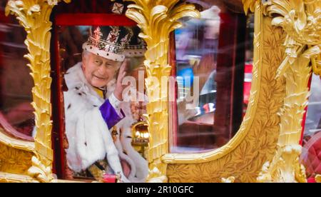King Charles III and Queen Camilla traveling in Gold Coach wearing their crowns, wave to the crowds from the Golden State Coach after their joint Coronation at Westminster Abbey. Westminster London. May 06, 2023. This state coach has been used at the coronation of every British monarch since William IV. Stock Photo