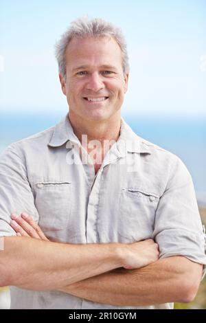 Enjoying some fresh sea air. Portrait of a mature man smiling happily at the camera. Stock Photo