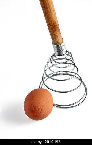 Beige chicken egg and spiral whisk. Ingredients for cooking isolated on white background. Stock Photo