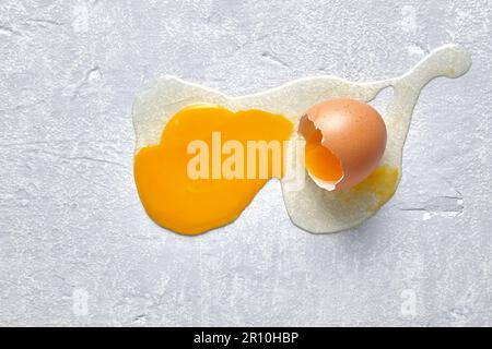 A fallen and broken chicken egg splashed across the concrete floor. Top view with copy space Stock Photo