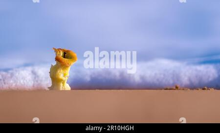 Red apple core lying on the shores of a sandy beach Stock Photo