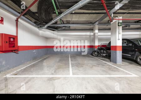 A few empty parking spaces in the basement of a residential building with red, gray paint and cement floors Stock Photo