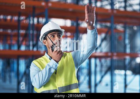 Life that higher. a handsome young contractor standing alone in the warehouse and using a walkie talkie. Stock Photo