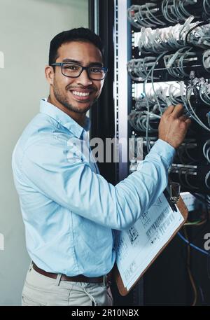 Ive got the technical side of things covered. a handsome young technician standing alone and adjusting the mainframe. Stock Photo