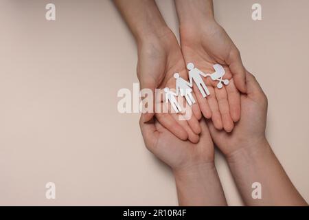 Couple holding paper family figures on beige background, top view with space for text. Insurance concept Stock Photo
