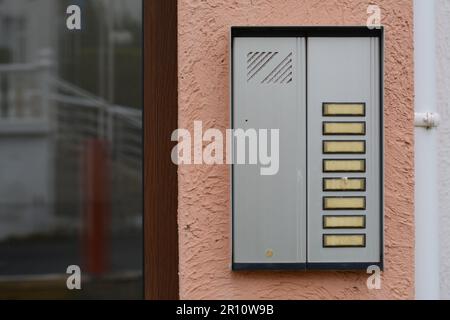 Modern intercom hanging on beige wall outdoors Stock Photo