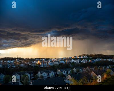 The contrast of sun-rays and dark clouds creates a dramatic scene over a US neighborhood before a bad weather hits. Stock Photo