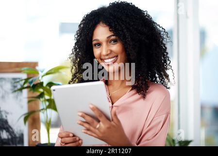 With wireless devices, desks are so last year. a young businesswoman using a digital tablet in a modern office. Stock Photo