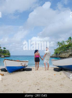 A couple of men and women in swimshorts and bikinis at Playa Lagun Beach Cliff Curacao, Lagun Beach Curacao a small island in the Caribbean.  Stock Photo