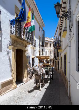 RONDA, ANDALUCIA, SPAIN - MAY 8 : Tourists enjoying a ride in a horse drawn carriage in Ronda Spain on May 8, 2014. Three unidentified people Stock Photo