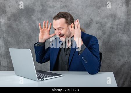 Surprised man working on laptop in blue suit Stock Photo