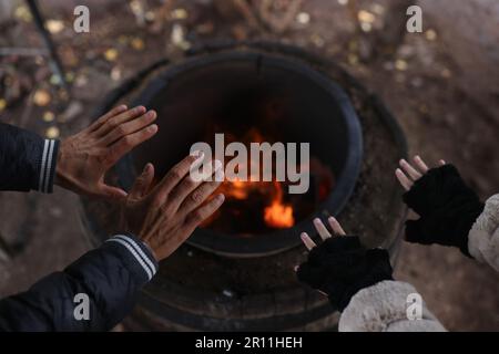 Male and female travelers warming hands near bonfire Stock Photo