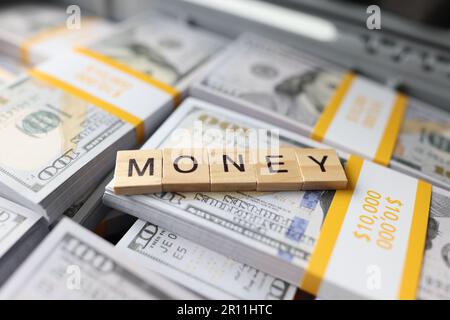 Money word collected with wooden blocks on pile of cash, suitcase with money Stock Photo