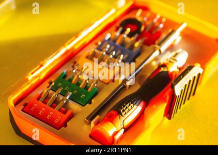 A set of various screwdrivers bits with different attachments in a plastic orange box. Different screwdrivers for repair work. Set of tools for small Stock Photo