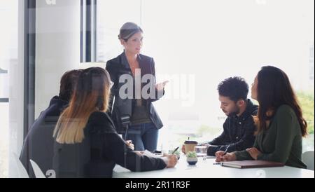 Talking through their teams goals for the month. a young businesswoman giving a presentation to her colleagues in an office. Stock Photo