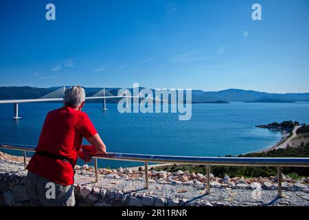 Rear view of senior man standing in front of Peljesac bridge, Croatia Stock Photo