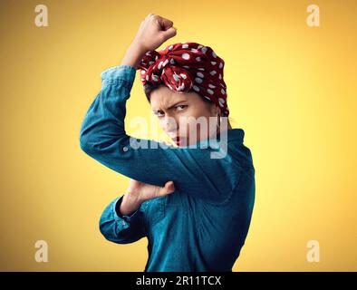 Pinup girl, strong and flexing muscle portrait in studio for support, women power and fashion. Angry female person show bicep on yellow background for Stock Photo