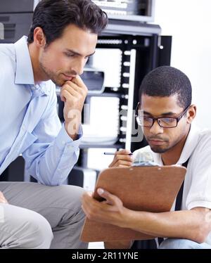 Teamwork, IT and men with clipboard in server room for maintenance, inspection and fixing. Checklist, network technician and tech support for Stock Photo