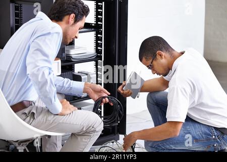 Server room, man or technician fixing electronics for hardware maintenance or working on glitch in office. IT support or worker with an electrician or Stock Photo