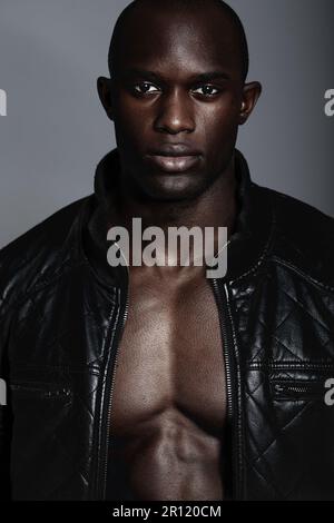 Fashion, portrait and black man in leather jacket in studio isolated on a gray background. African male model, serious face and coat, confidence and Stock Photo
