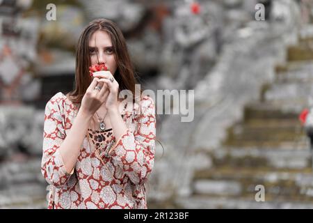 religion of the soul, from below the full body of a barefoot woman with curly hair in casual clothes, near the temple of indonesia 4k. Stock Photo