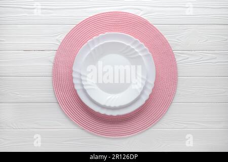 Empty plate and round pink napkin on a white wood table. Top view. Food template, copy space. Flat design, mockup. Layout, frame. Place setting, servi Stock Photo