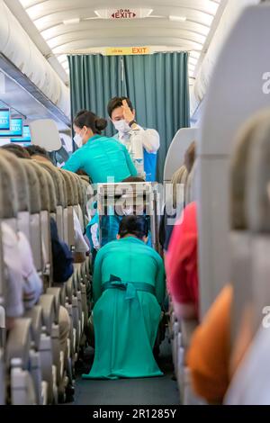 Vietnam Airlines cabin crew wearing traditional ao dai uniform on flight Stock Photo