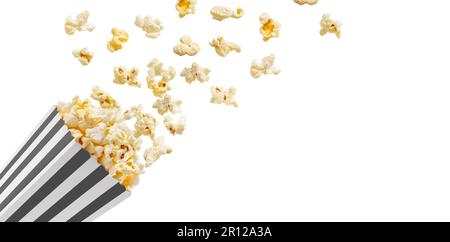 Popcorn flying out of black white striped paper box isolated on white background with copy space. Splash, levitation of popcorn grains. Stock Photo