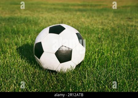 Classic soccer ball, typical black and white pattern, placed on the spot of the stadium turf. Traditional football ball on the green grass field of ar Stock Photo