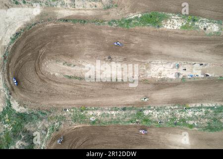 Drone aerial of a motocross race on a dirt curvy sport track. Aerial view of high-speed racing. Athletes in action. Stock Photo