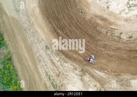 Drone aerial of a motocross race on a dirt curvy sport track. Aerial view of high-speed racing. Athletes in action. Stock Photo