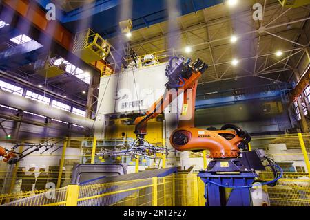 Nizhny Novgorod, Russia - November 21, 2020: GAZ car production plant. Kuka robot manipulator take metal car panel to stamping press Stock Photo