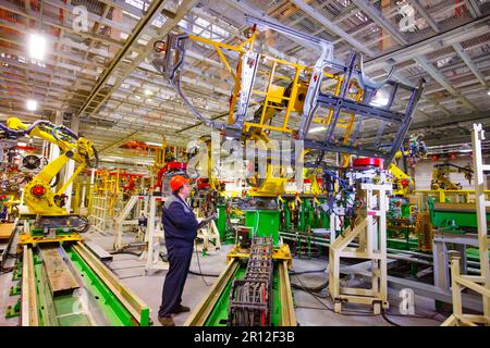 Nizhny Novgorod, Russia - November 21, 2020: GAZ car production plant. Operator adjust automatic welding line. Steel side part of bus body on top Stock Photo