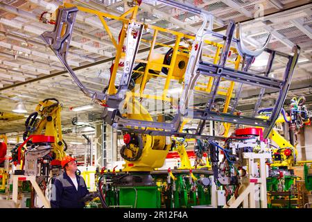 Nizhny Novgorod, Russia - November 21, 2020: GAZ car production plant. Operator adjust automatic welding line. Side part of bus body on top Stock Photo