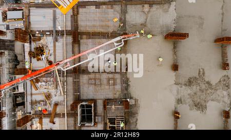 Aerial view of a construction site with workers pouring and leveling concrete. Construction of a multi-storey reinforced concrete house. Stock Photo