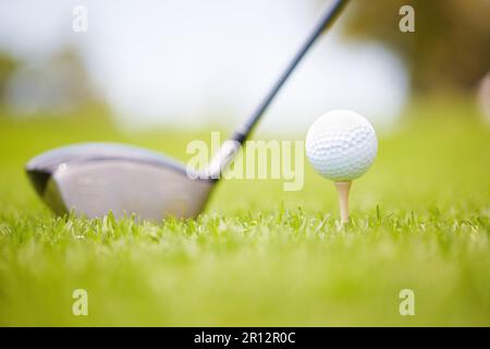 Getting ready to hit the ball. Golf ball carefully balanced on a golf tee with a club in the background. Stock Photo