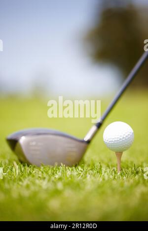 Club and golf ball. Golf ball carefully balanced on a golf tee with a club in the background. Stock Photo