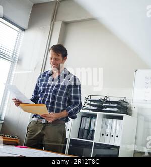 This contract is perfect. a handsome businessman looking over some documents in his office. Stock Photo