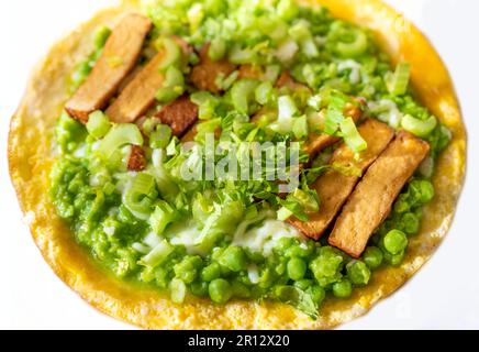 Egg omelette with mashed fresh green pea and celery stalk and smoked tofu on white plate, closeup. Stock Photo