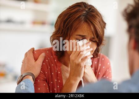 When the pain becomes too much. a woman being comforted by her husband as she cries. Stock Photo