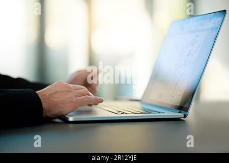 Working on something big. an unrecognizable businessman working on his laptop in the office. Stock Photo