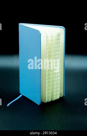 blue standing partially open notebook on a black background Stock Photo