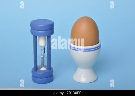 Boiled egg and hourglass on a blue background Stock Photo