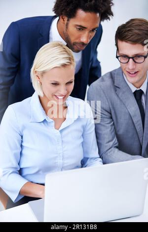 The news is looking good. three smiling colleagues looking at a digital tablet together. Stock Photo