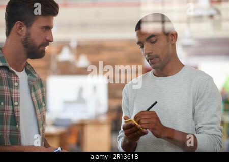 Let me jot those ideas down. two colleagues discussing ideas together. Stock Photo