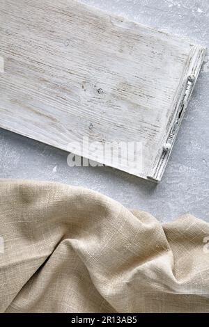 A white wooden tray and a coarse linen napkin on a gray concrete table. Top view with copy space Stock Photo