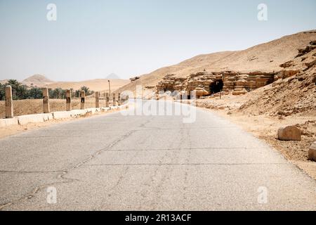 Winding black asphalt road through the sand dunes of oasis, Stock Photo