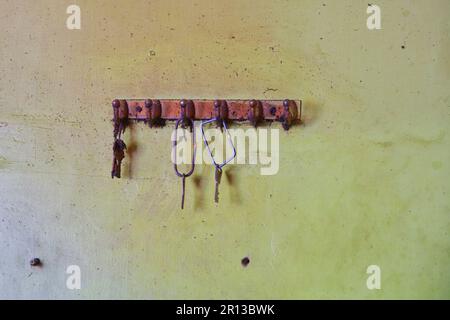 Dusty hook with keys on the dirty green wall of an old building Stock Photo